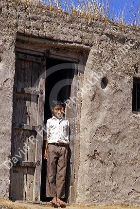 Boy standing at the door of a mud covered shack at a Plains village near Aurangabad, India.