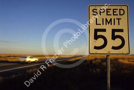 Speed limit 55 sign with traffic on the interstate in Idaho.
