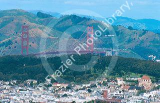 The Golden Gate Bridge in San Francisco, California towers above a residential area and golf course with the Marin Headlands in the background.
