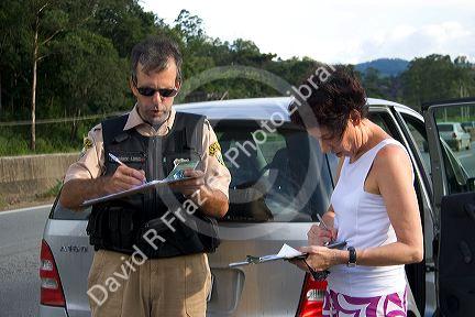 Brazilian federal police and a woman fill out paperwork at the scene of a traffic accident near Sao Paulo, Brazil.
