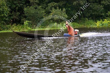 Man riding in a boat on the Arasa River in the Amazon jungle near Manaus, Brazil.