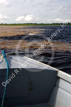 The bow of a boat at the confluence of the Amazon River and the Rio Negro at Manaus, Brazil.