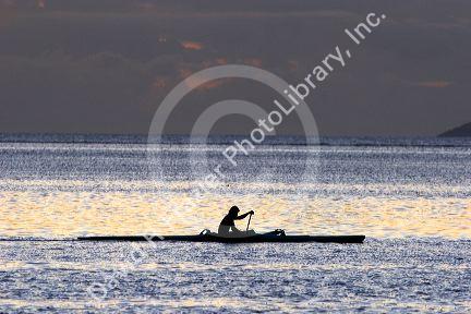 Outrigger canoe at sunset off the island of Tahiti.