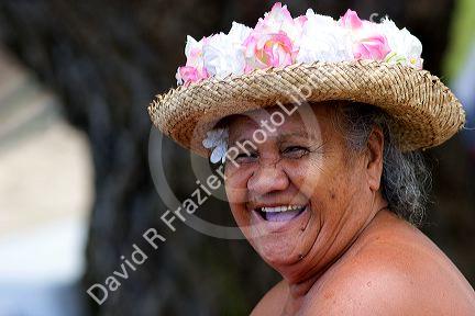 An elderly Tahitian woman smiling wearing a colorful hat on the island of Moorea.