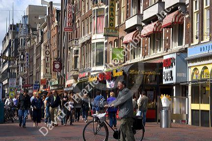 People walk and ride bicycles on the Damrak Strasse in Amsterdam, Netherlands.