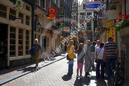 People and store fronts on a walking street in the Red Light District of Amsterdam, Netherlands.