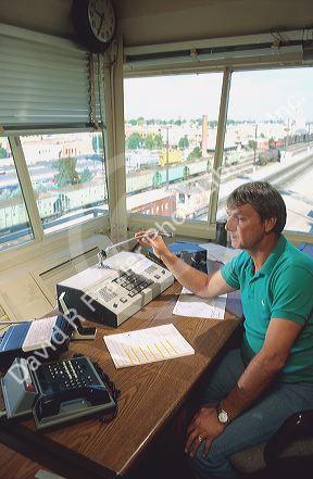 Railroad dispatcher at work in freight yard control tower.