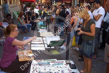 Customer purchasing jewelry from a street vendor in Paris, France.