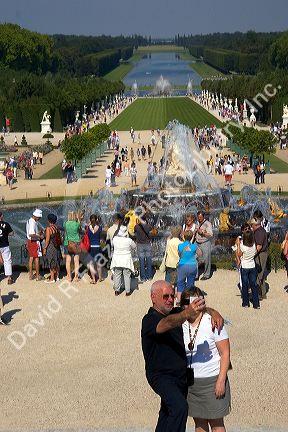 Tourists take photographs by fountains in the formal gardens at The Palace of Versailles at Versailles in the department of Yvelines, France.