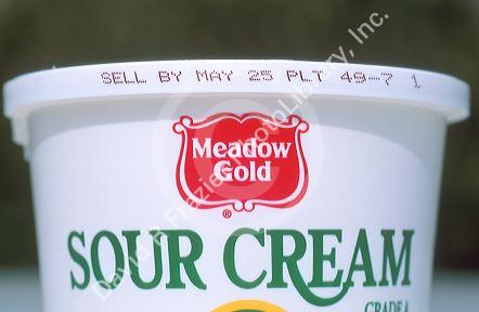 Sell by date on a sour cream container.