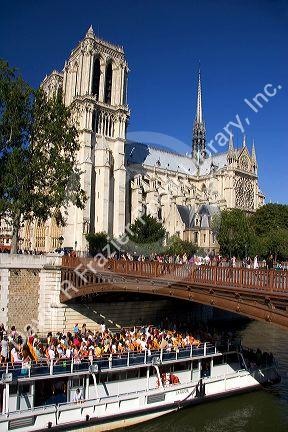 A boat tour on the river seine passes the Norte Dame cathedral in Paris, France.