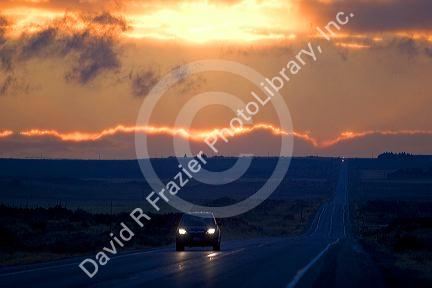 Car driving at sunset on highway 20 near Idaho Falls, Idaho.