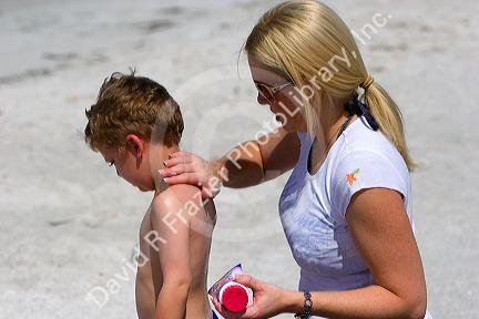 Mother applying sunscreen to her son on the beach at St. Petersburg, Florida. MR