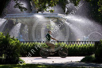 Bicyclist rides past a large water fountain in Forsyth Park in the historic district of Savannah, Georgia.