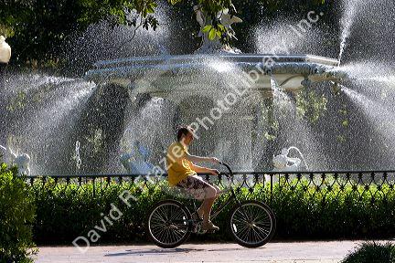 Bicyclist rides past a large water fountain in Forsyth Park in the historic district of Savannah, Georgia.