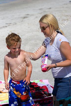 Mother applying sunscreen to her son at the beach in St. Petersburg, Florida. MR