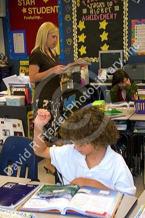 Teacher and fourth grade student raising his hand in a classroom at a public school in Tampa, Florida.