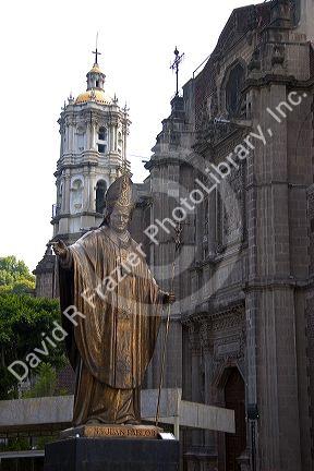 A brass statue of Pope John Paul II in front of the old Basilica of Guadalupe in Mexico City, Mexico.