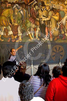 A tour guide showing tourists a mural painted by Diego Rivera at the National Palace in Mexico City, Mexico.
