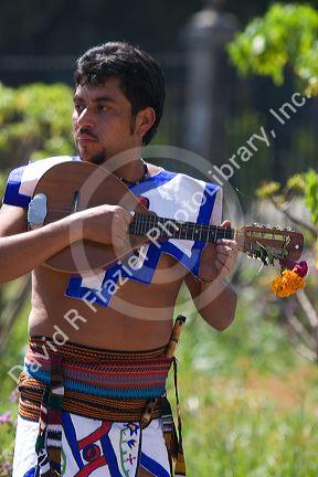 Aztec indian man in tradional dress playing the mandolin during a celebration for the Day of Dead in Mexico City, Mexico.