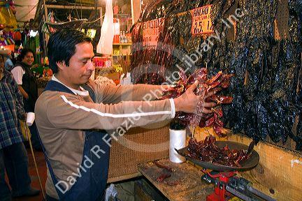 Vendor using a scale to weigh dried peppers at the Merced Market in Mexico City, Mexico.