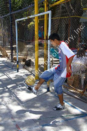 Teenage boy kicking a soccer ball in the La Boca barrio of Buenos Aires, Argentina.