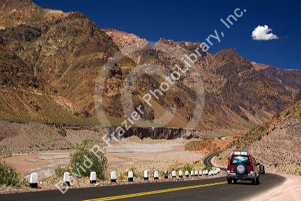 Vehicles drive on a highway along the Mendoza River in the Andes Mountain Range west of Upsallata, Argentina.