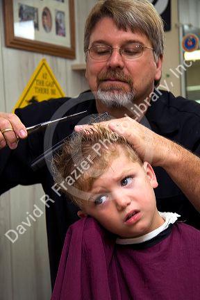 Barber giving a three year old boy a haircut in Tampa, Florida. MR