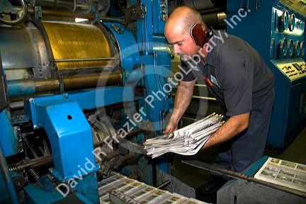 Pressman pulling newspapers from the rotary printing press for the Houston Chronicle in Houston, Texas.