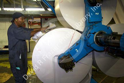 Pressman loading large rolls of paper on to a rotary printing press for the Houston Chronicle in Houston, Texas.