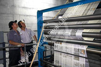 Pressmen inspect newspapers being printed on a rotary printing press for the Houston Chronicle in Houston, Texas.