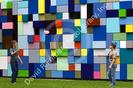 Woman play frisbee in front of the Synchronicity of Color public art installation by Margo Sawyer at Discovery Green public park in Houston, Texas.