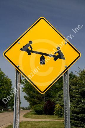 Road sign depicting a seesaw, warning of children playing in Gratiot County, Michigan.