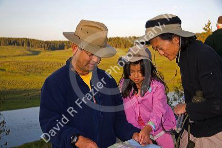 Asian family mapping out their visit to Yellowstone National Park, Wyoming. MR