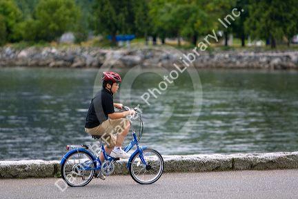Asian boy riding a bicycle at Stanley Park in Vancouver, British Columbia, Canada.