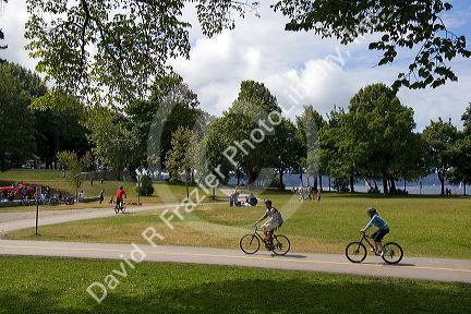 Bicyclists ride along the Seawall path in Stanley Park at Vancouver, British Columbia, Canada.