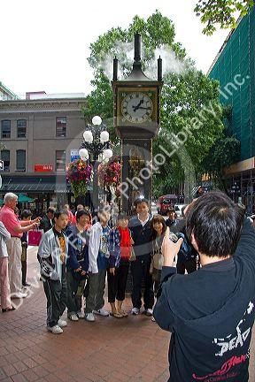 Asian tourists have their photo taken in front of the Gastown Steam Clock located in Vancouver, British Columbia, Canada.