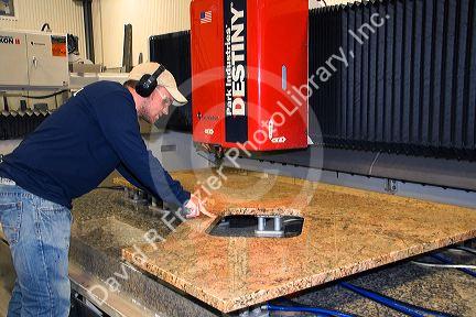 Worker custom cutting a granite countertop at The Shaker Hill Granite Company located in the town of Enfield, New Hampshire, USA.