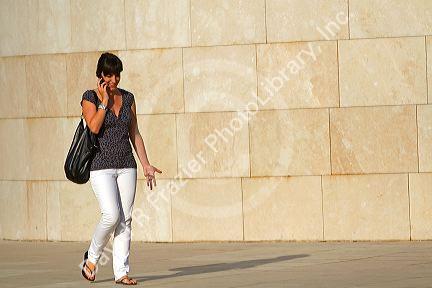 Woman talking on a cell phone in front of the Guggenheim Museum in the city of Bilbao, Biscay, Basque Country, northern Spain.