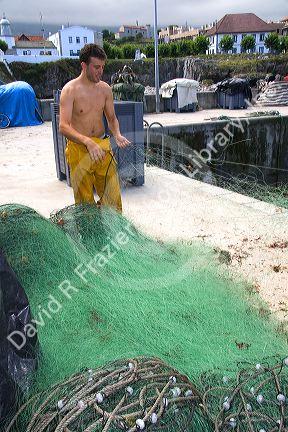 Commercial fisherman with fishing net in the harbor at Llanes, Asturias, Spain.