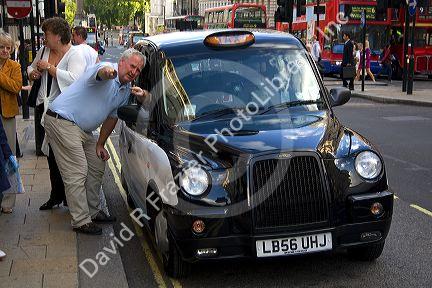 Hackney taxi cab driver giving directions to a pedestian in the city of London, England.