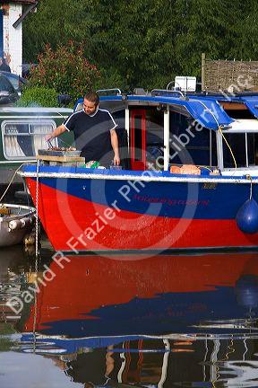 Man cooking on a narrowboat moored in the River Avon at Stratford-upon-Avon, Warwickshire, England.