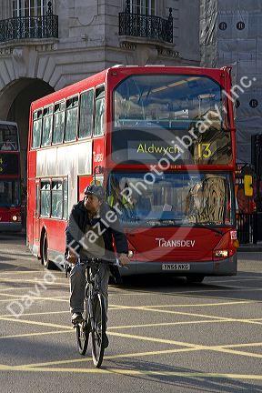 Bicyclist and a double decker bus in the city of London, England.