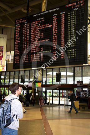 Young man looks at departure schedule board in South Station located in Dewey Square, Boston, Massachusetts, USA.