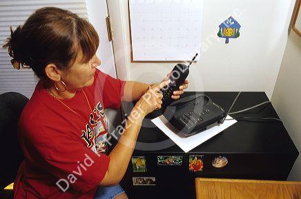 Woman using a cordless telephone with answering machine.