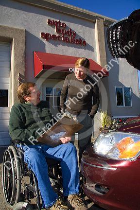 Handicapped insurance claims adjuster with customer assessing the damage of her automobile in Boise, Idaho, USA. MR