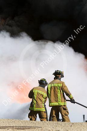 Firefighters using fire retardant foam to put out a jet fuel fire at an airport training facility in Boise, Idaho, USA.