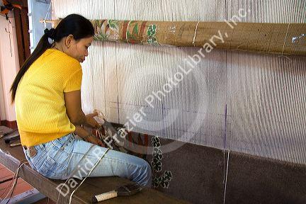 Vietnamese woman manufacturing woven rugs at a craft center in Hoi An, Vietnam.