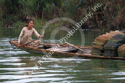 Vietnamese woman transporting fishing nets by boat on the Perfume River at Hue, Vietnam.