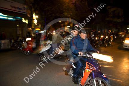 Vietnamese people ride motorbikes in Hanoi, Vietnam.